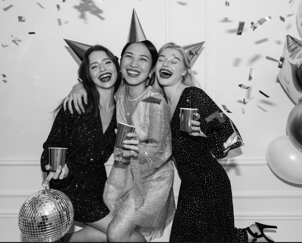 Group of friends with photo booth props and metallic backdrop