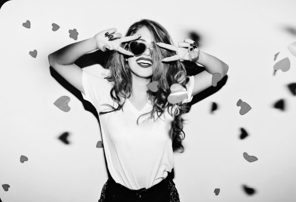 Joyful woman with heart confetti and sunglasses